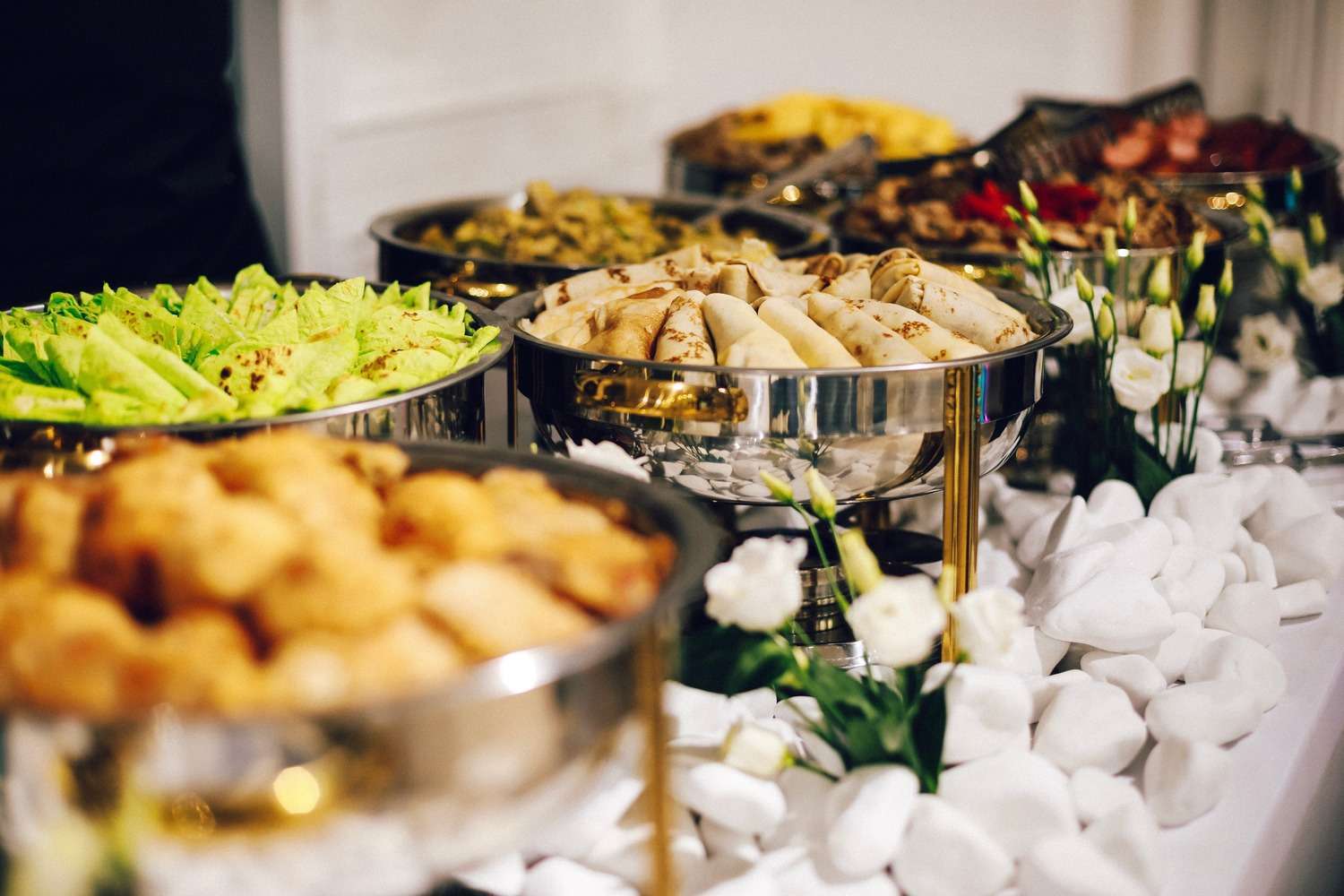 A Colbeh buffet dressed with white lisianthus and gold chafing stands